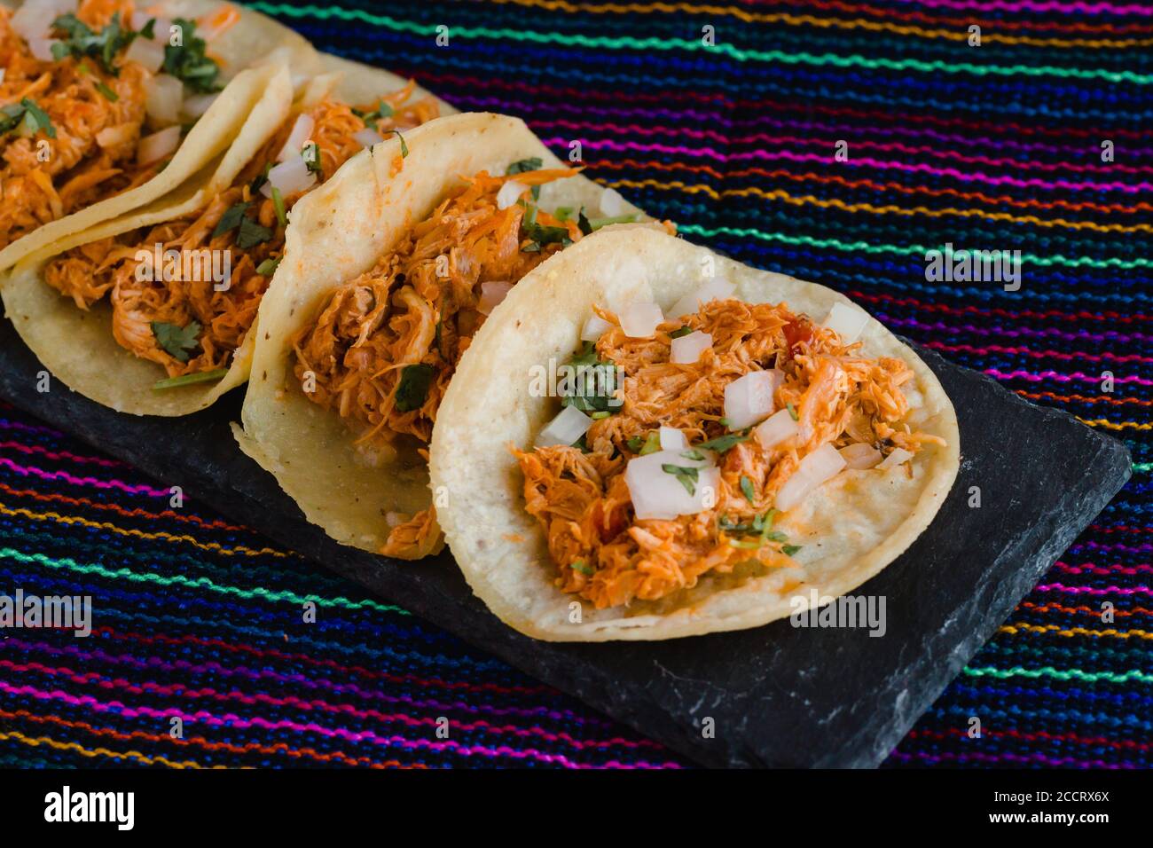 Mexican tacos filled with tinga de pollo on a traditional textile background Stock Photo