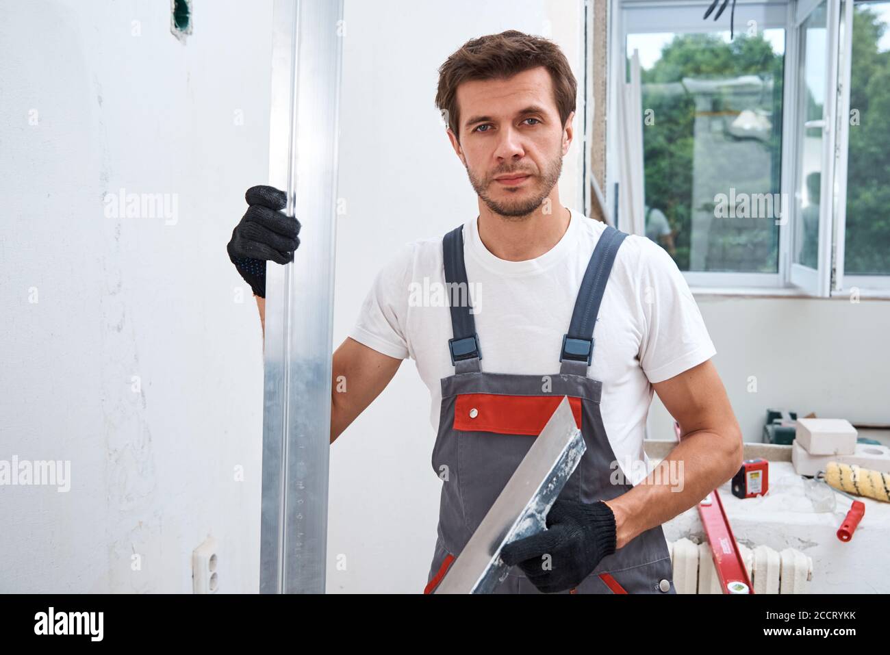 Male worker plastering a wall using a long spatula. Renovation concept Stock Photo