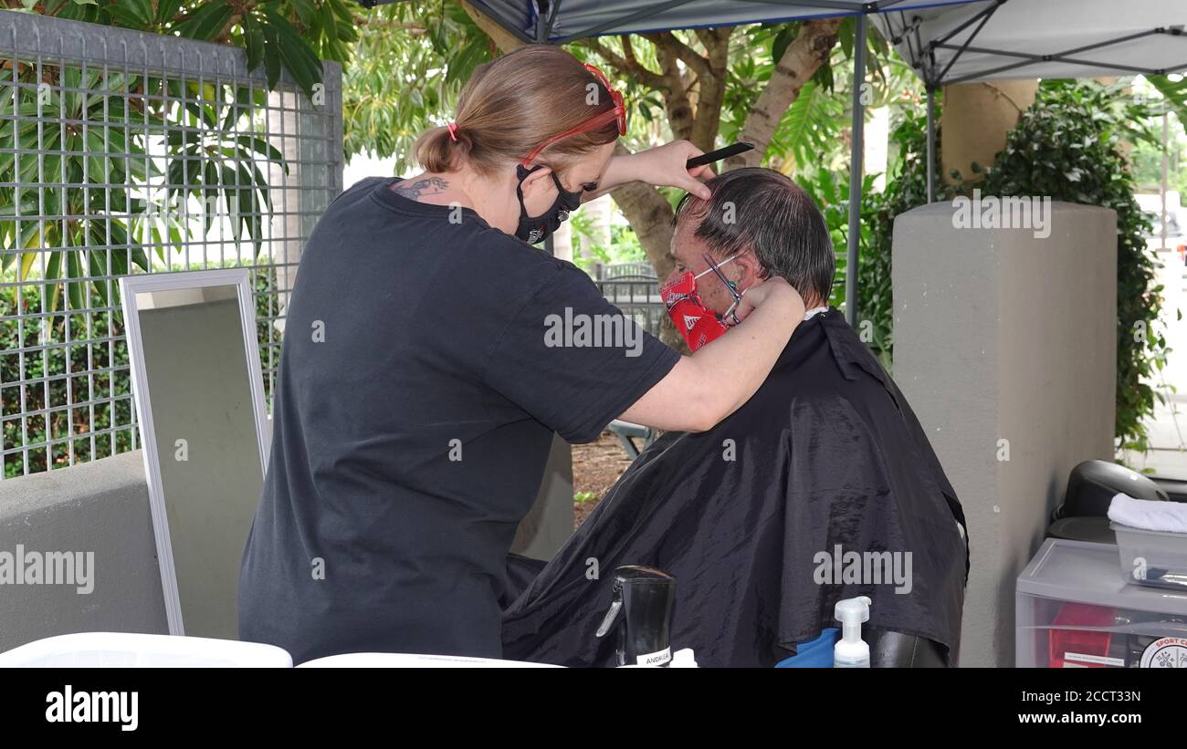 An older man is getting a haircut outside as Sports Clips hair salon moved operations outdoors to avoid Covid-19 shutdown. Stock Photo