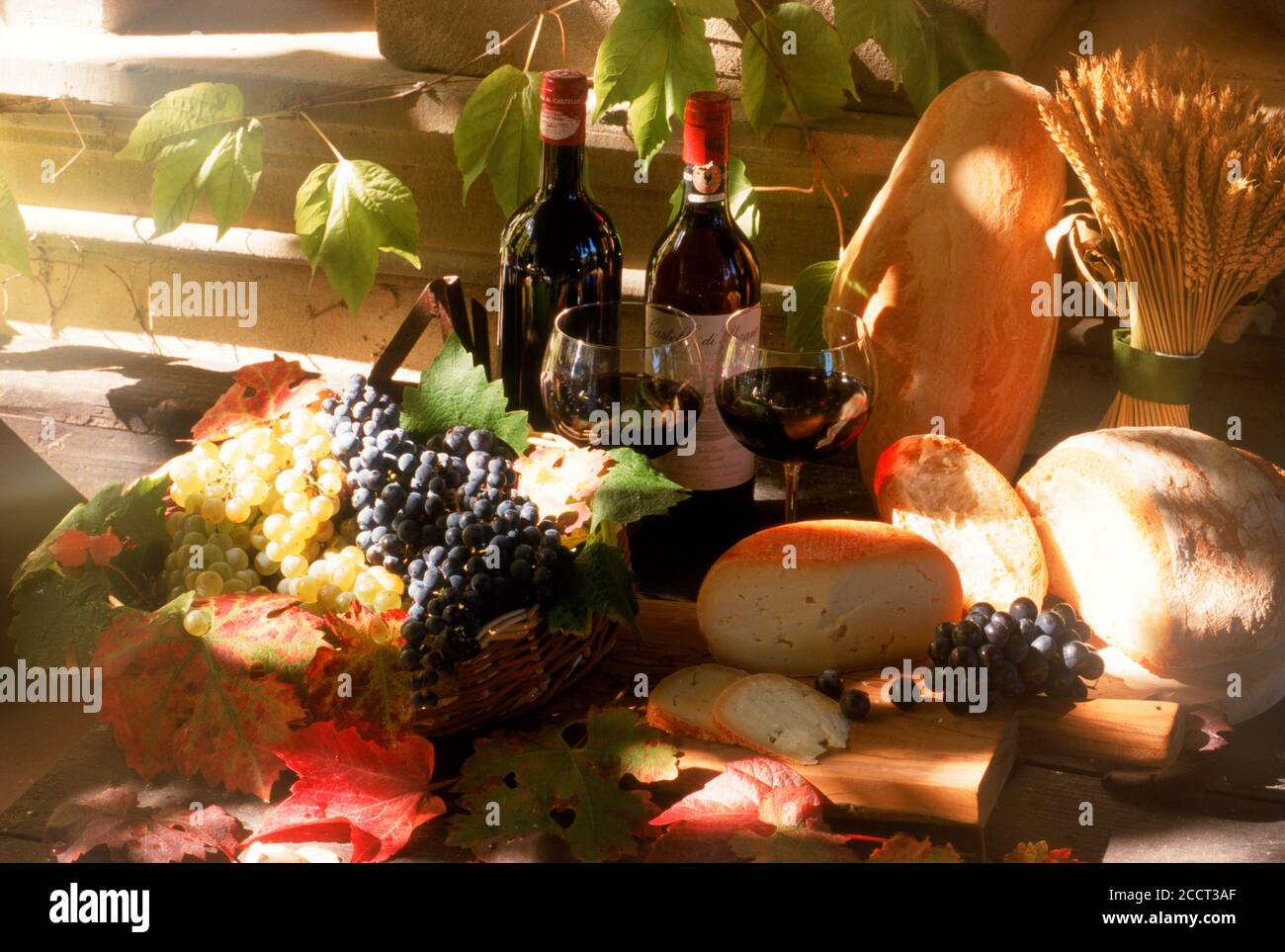 Bottles of Chianti wine with grapes bread and cheese and wheat stalks at Chateau Uzzano in Tuscany Italy Stock Photo
