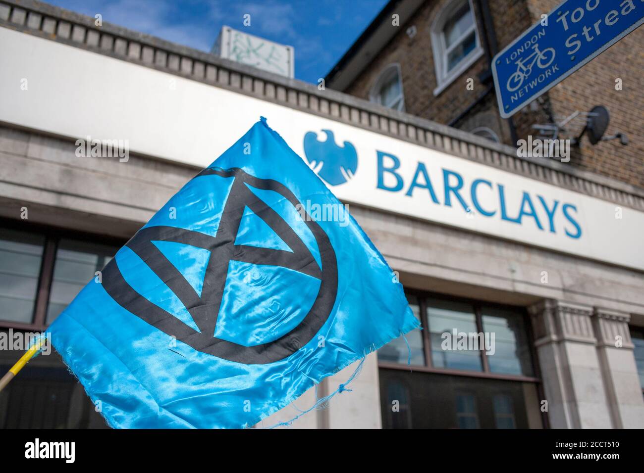 Blue Extinction Rebellion flag outside Barclays Bank in Balham, South London. XR continue to protest against Barclays for crimes against the planet. Stock Photo