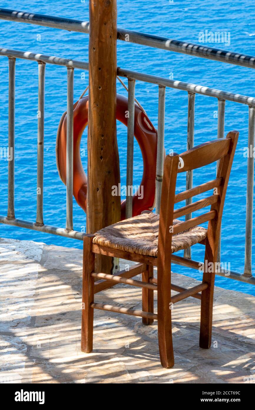 an empty chair outdoors and a life ring next to the sea on the greek island of zakynths on zante greece. Stock Photo