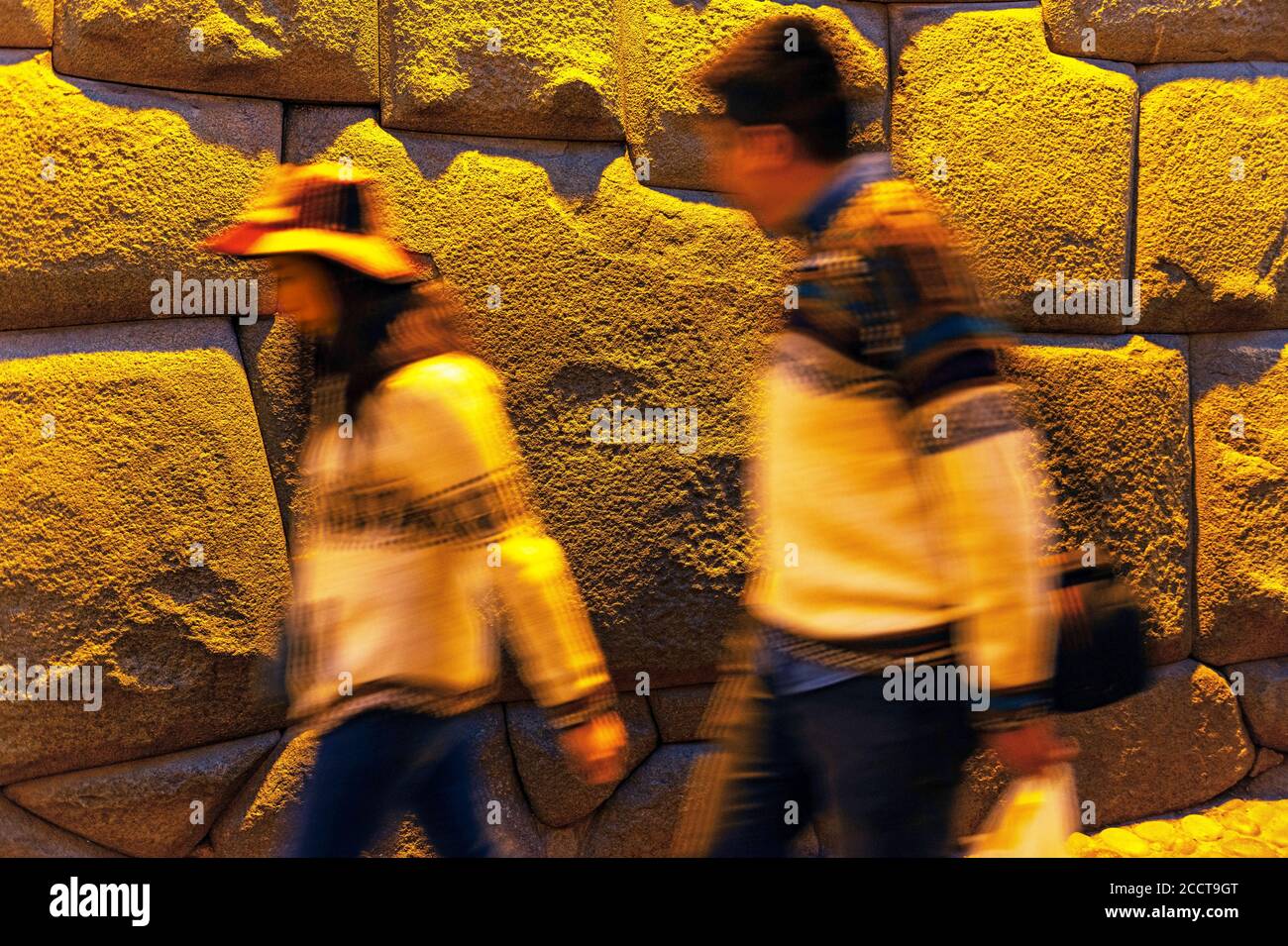 Tourists passing by the Twelve Angle Stone in the Hatun Rumiyok street at night, Cusco, Peru. Stock Photo