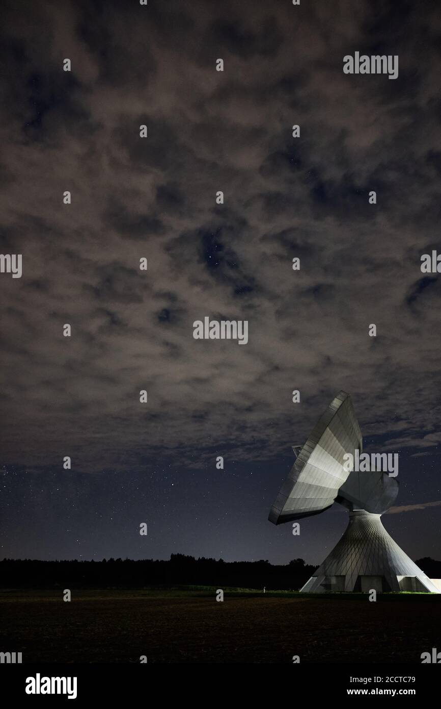 A dish antenna under a cloudy night sky Stock Photo