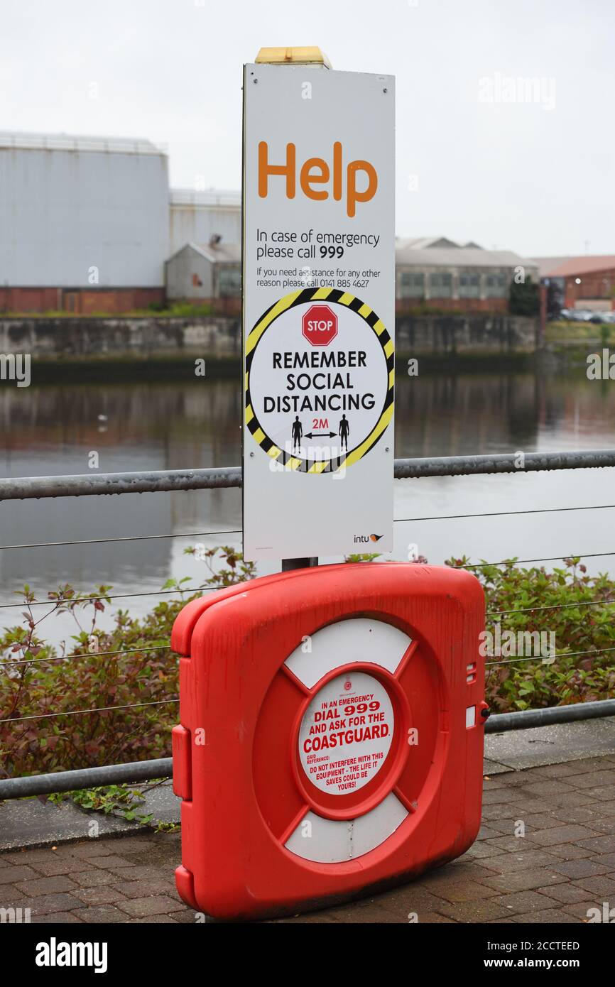 Emergency point with lifebelt for river rescue and a reminder to keep 2 meters socially distant in Braehead, Scotland Stock Photo