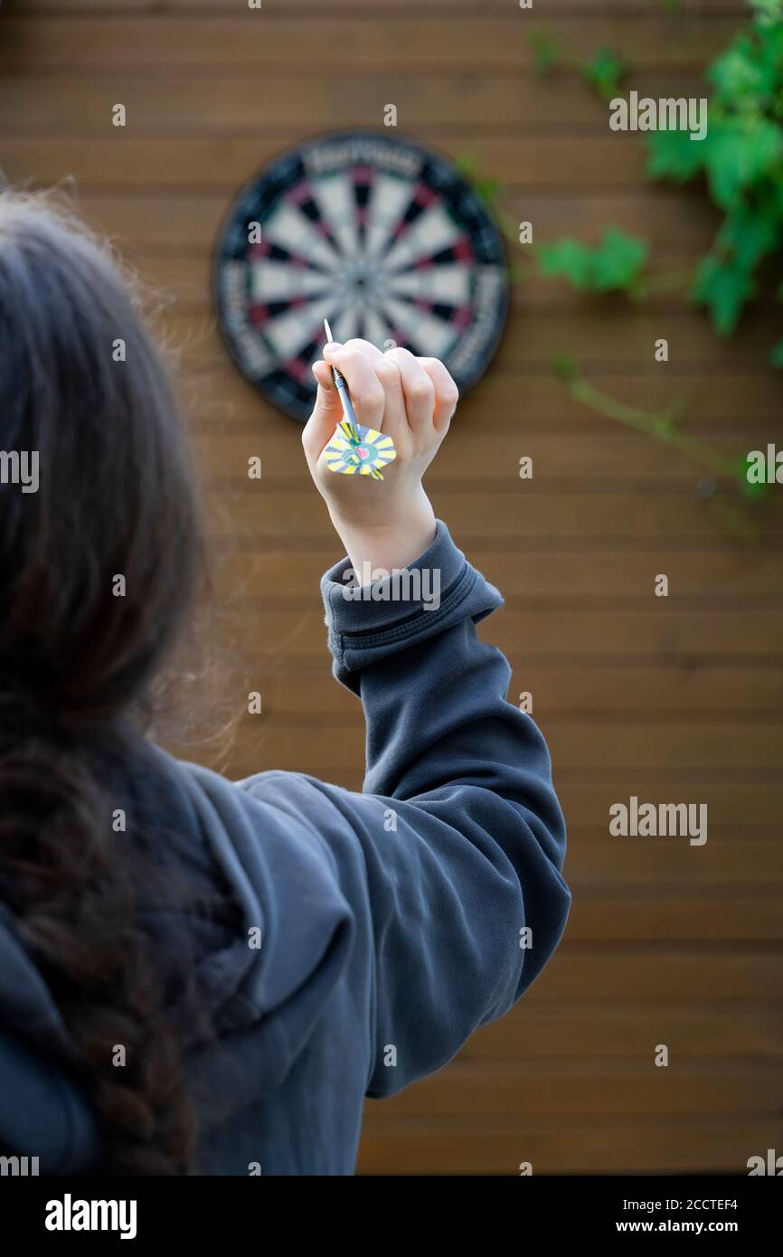 Unrecognizable girl with her back to us with dart arrow in her hand is