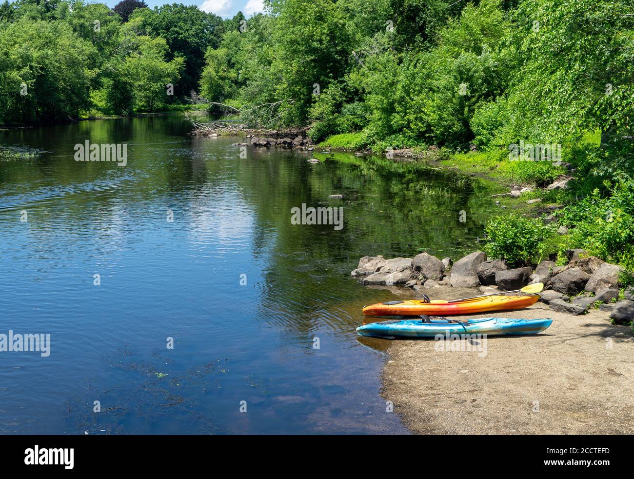 Kayaks site on shore by a small stream Stock Photo