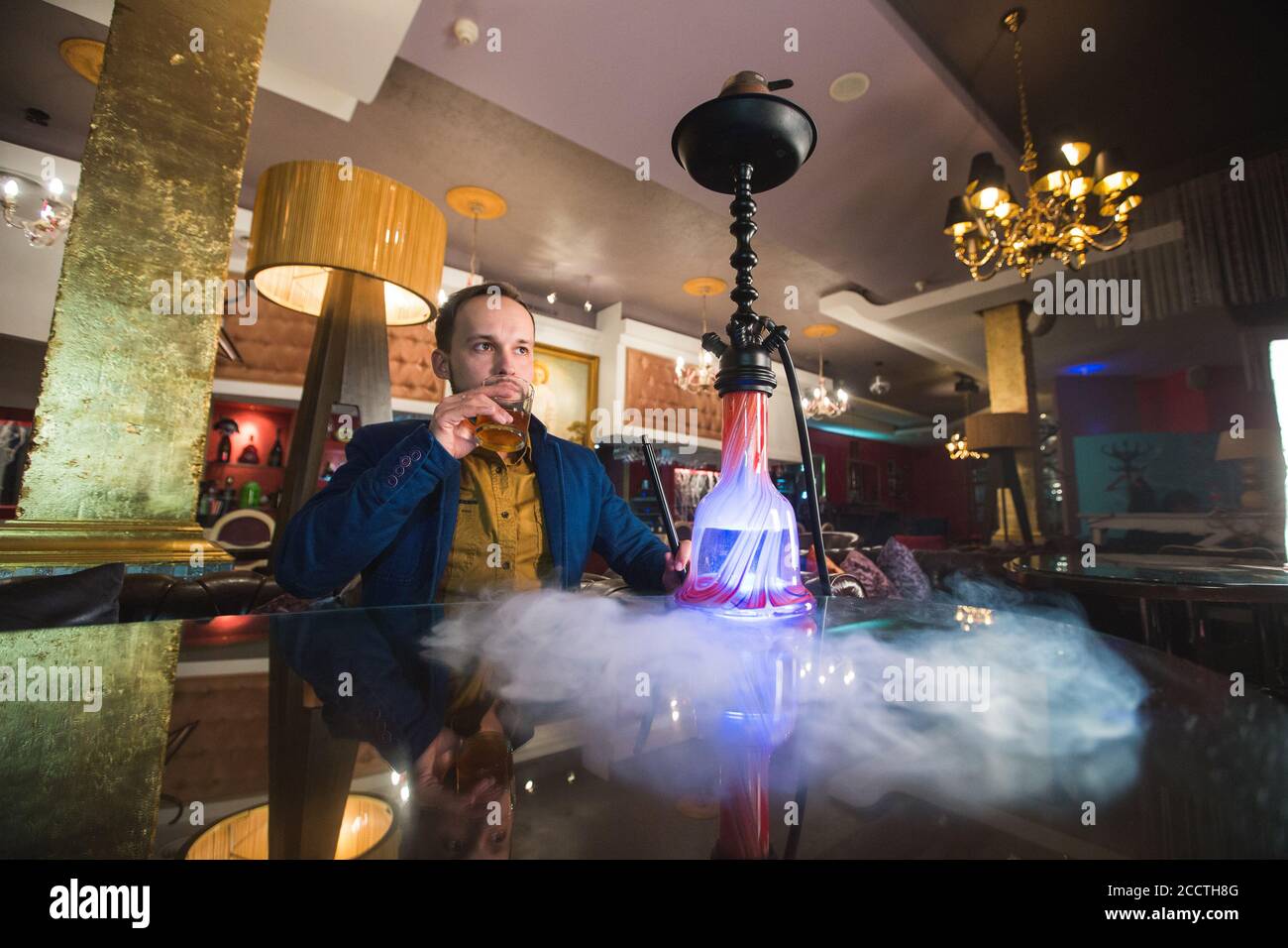 Smoking hookah. Man is blowing smoke in a cafe. Stock Photo
