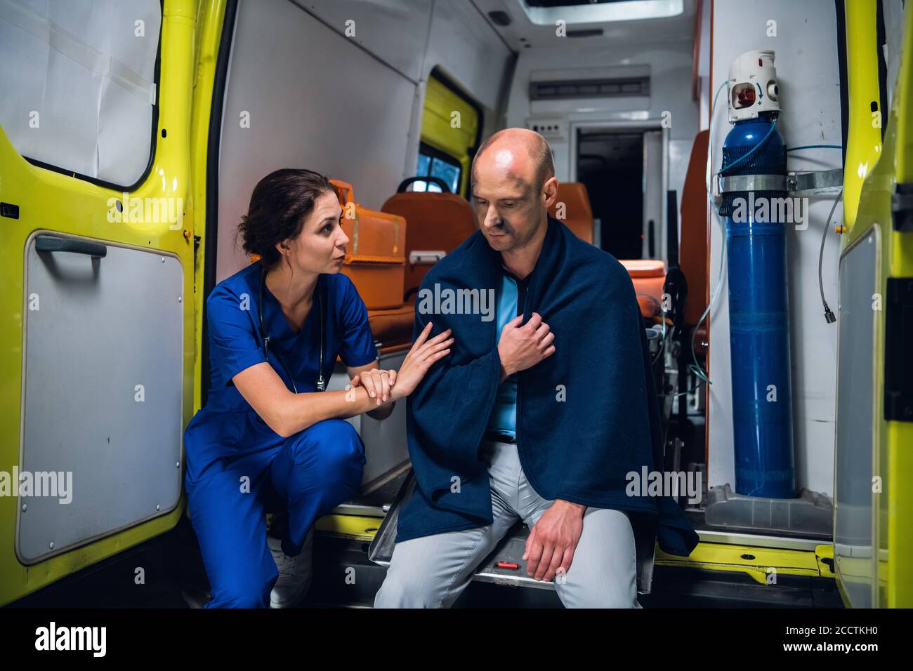 Nurse talking friendly to an injured man in a blanket in an ambulance
