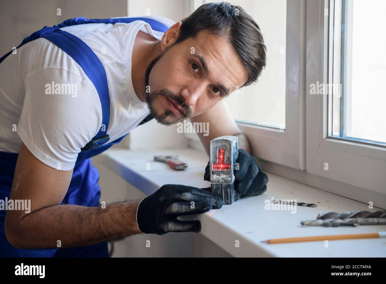 The man measures the distance from the window with a level Stock Photo