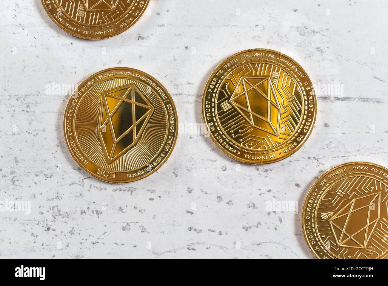 Overhead shot, golden commemorative EOS - EOSIO  cryptocurrency - coins on white stone board Stock Photo