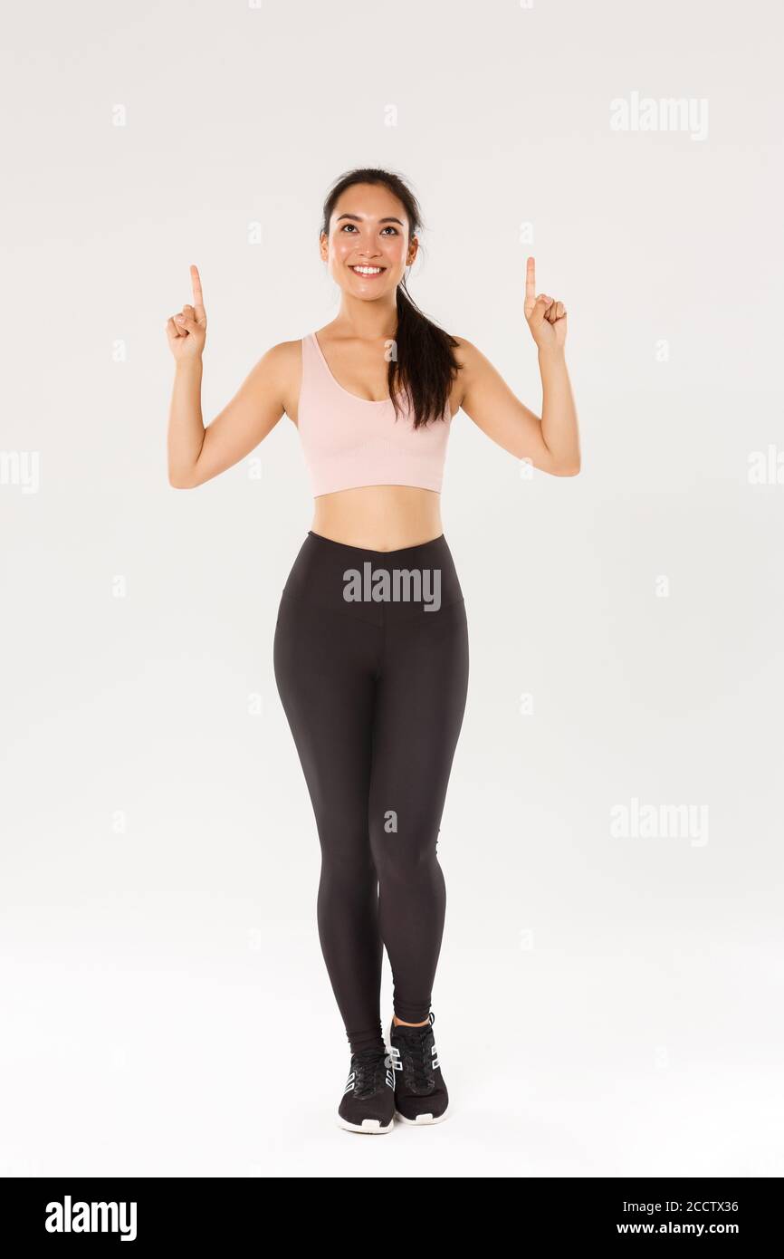 Full length of cute asian girl with perfect body in sportswear, female  athlete like sport, pointing fingers up and looking at advertisement with  Stock Photo - Alamy