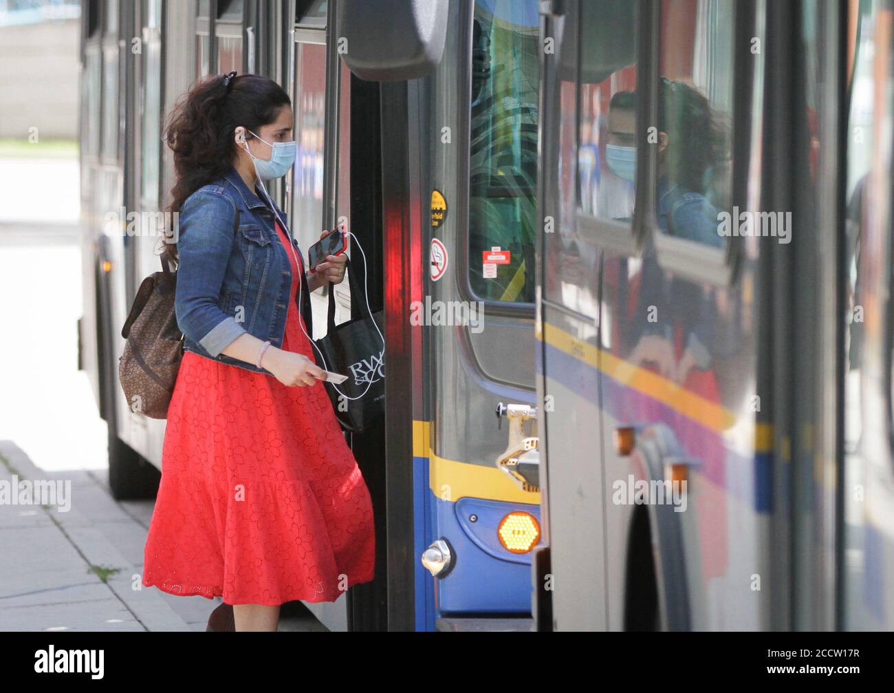 Vancouver, Canada. 24th Aug, 2020. A woman wearing a face mask gets on a bus in Vancouver, British Columbia, Canada, on Aug. 24, 2020. Anyone on board a TransLink or British Columbia (BC) Transit bus, boat or train and passengers on board BC Ferries vessels are required to wear a face mask beginning Monday to help stop the spread of COVID-19. Credit: Liang Sen/Xinhua/Alamy Live News Stock Photo