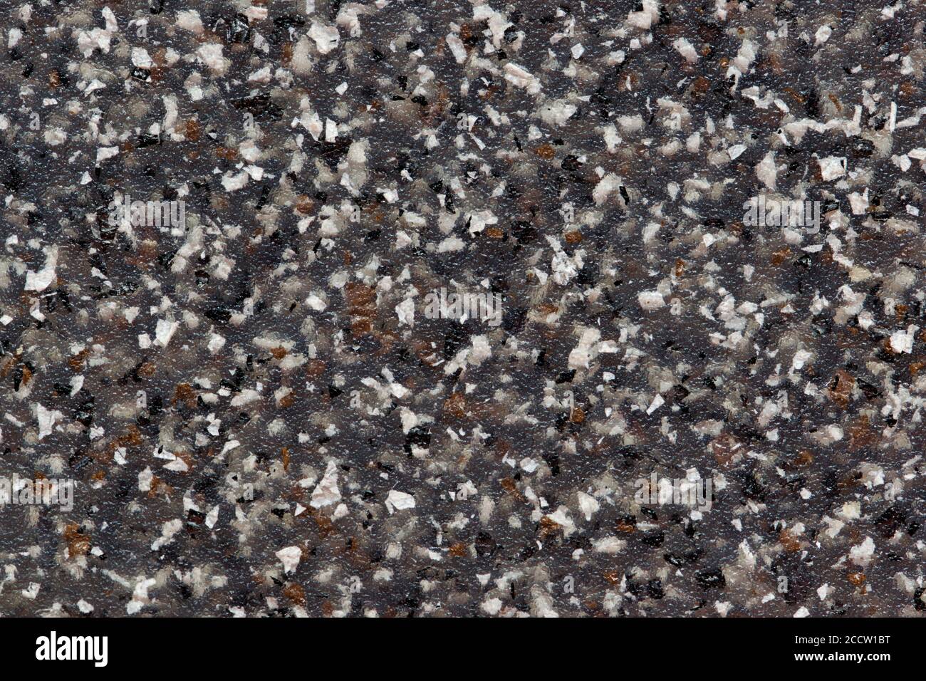 Black plastic with colored speckles throughout. Solid full frame abstract image for background and wallpaper. Close up macro view. Stock Photo