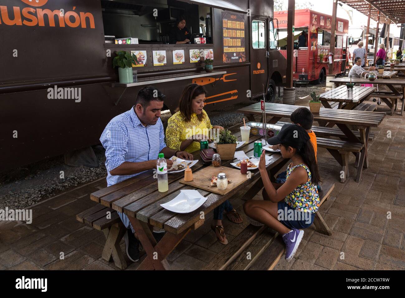 A familiy in an outdoor eating area with mobile food vender's trucks in Tijuana, Mexico. Stock Photo