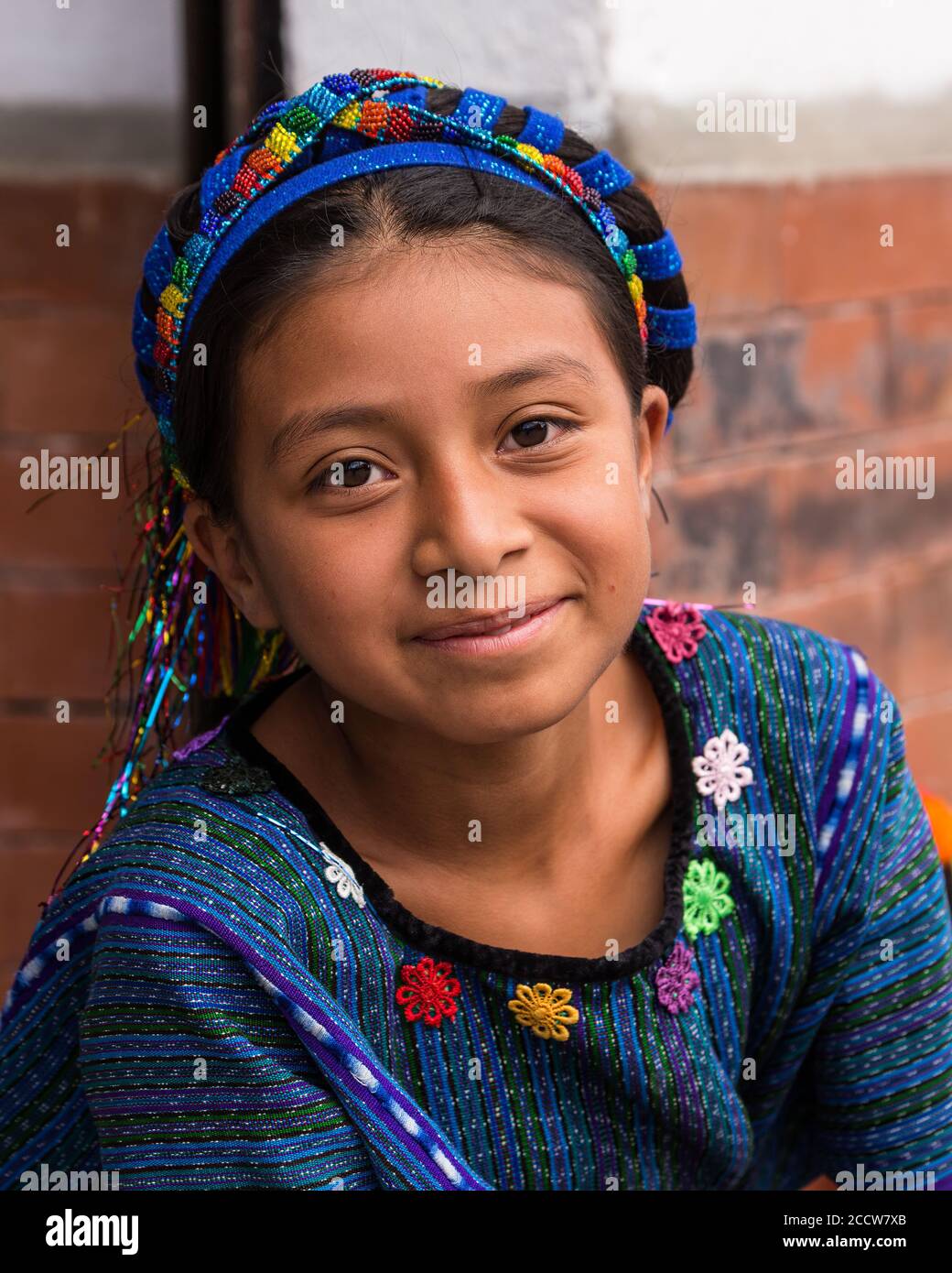 A young Cakchiquel Mayan girl in the traditional dress of San Antonio Palopo, Guatemala, including a blue woven huipil blouse and cinta or decorative Stock Photo