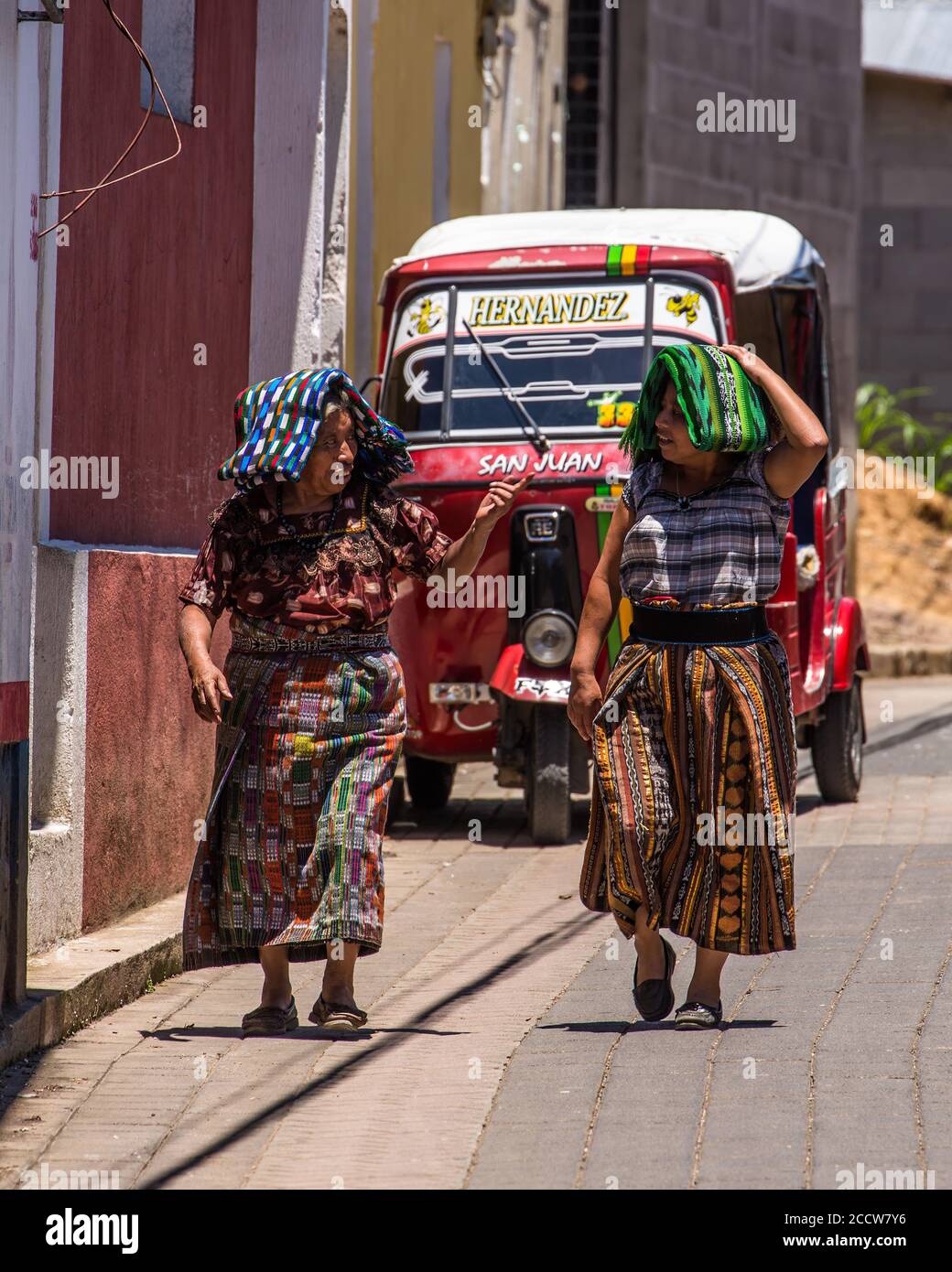 Two Tzutujil Mayan woman in traditional dress walk along a street in San Juan la Laguna, Guatemala. Stock Photo