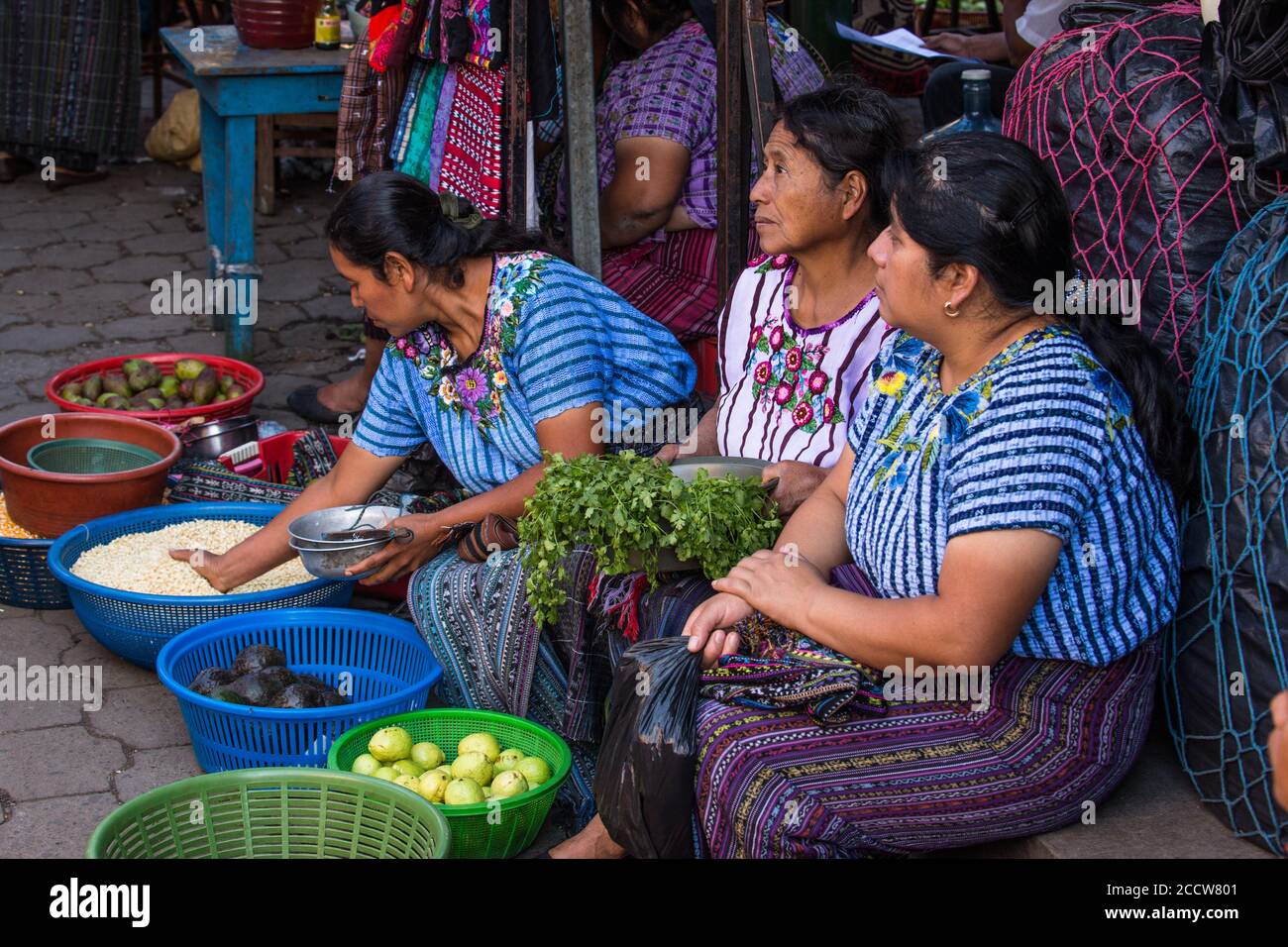 Three Tzutujil Mayan women in traditional dress sell produce in the weekly open market in Santiago Atitlan, Guatemala. Stock Photo