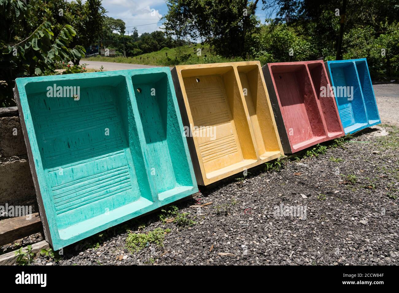 Brightly colored cement sinks or basins for washing clothes by hand along a roadside in rural