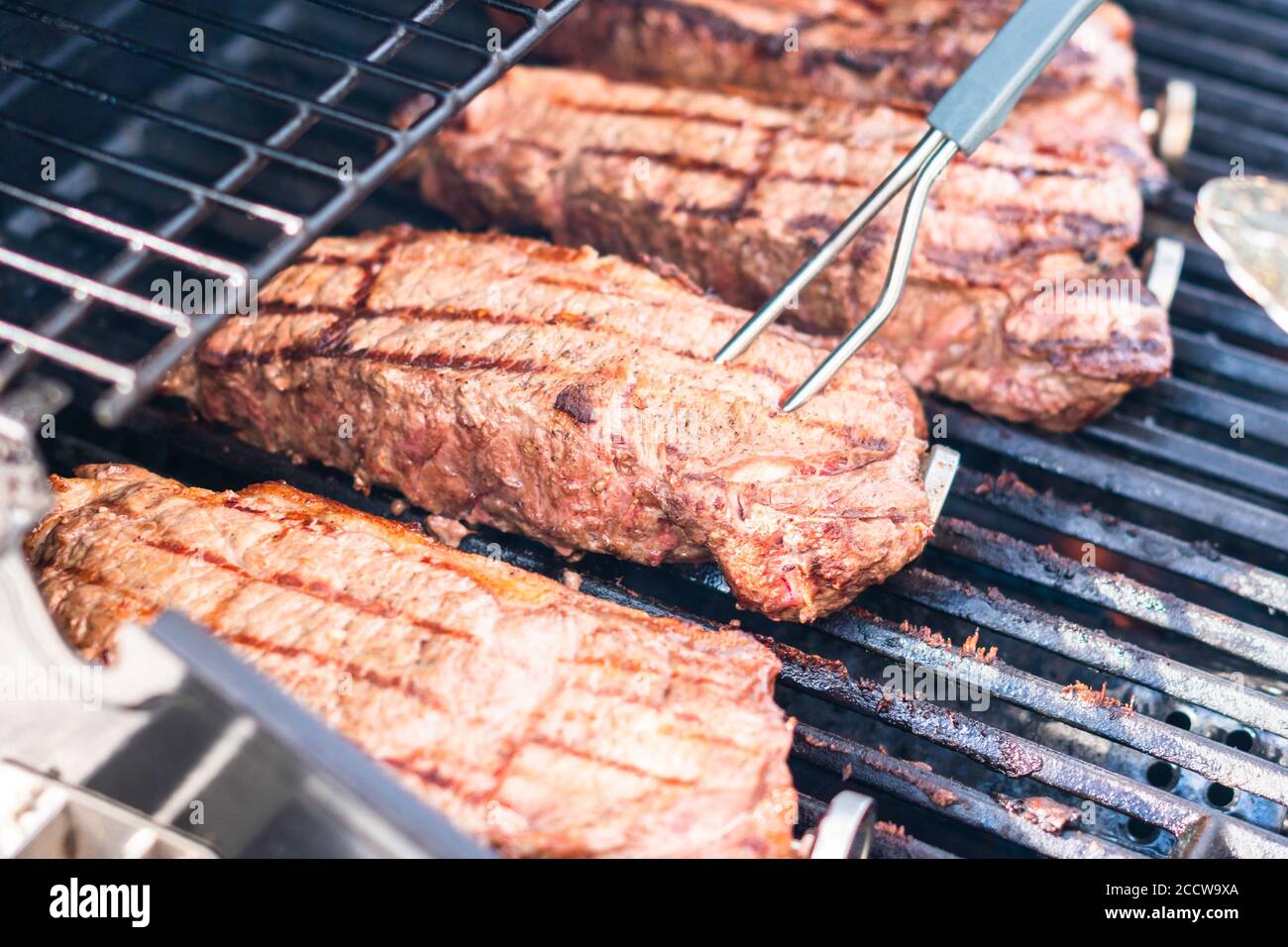 Grilling New York strip steak on outdoor gas grill Stock Photo Alamy