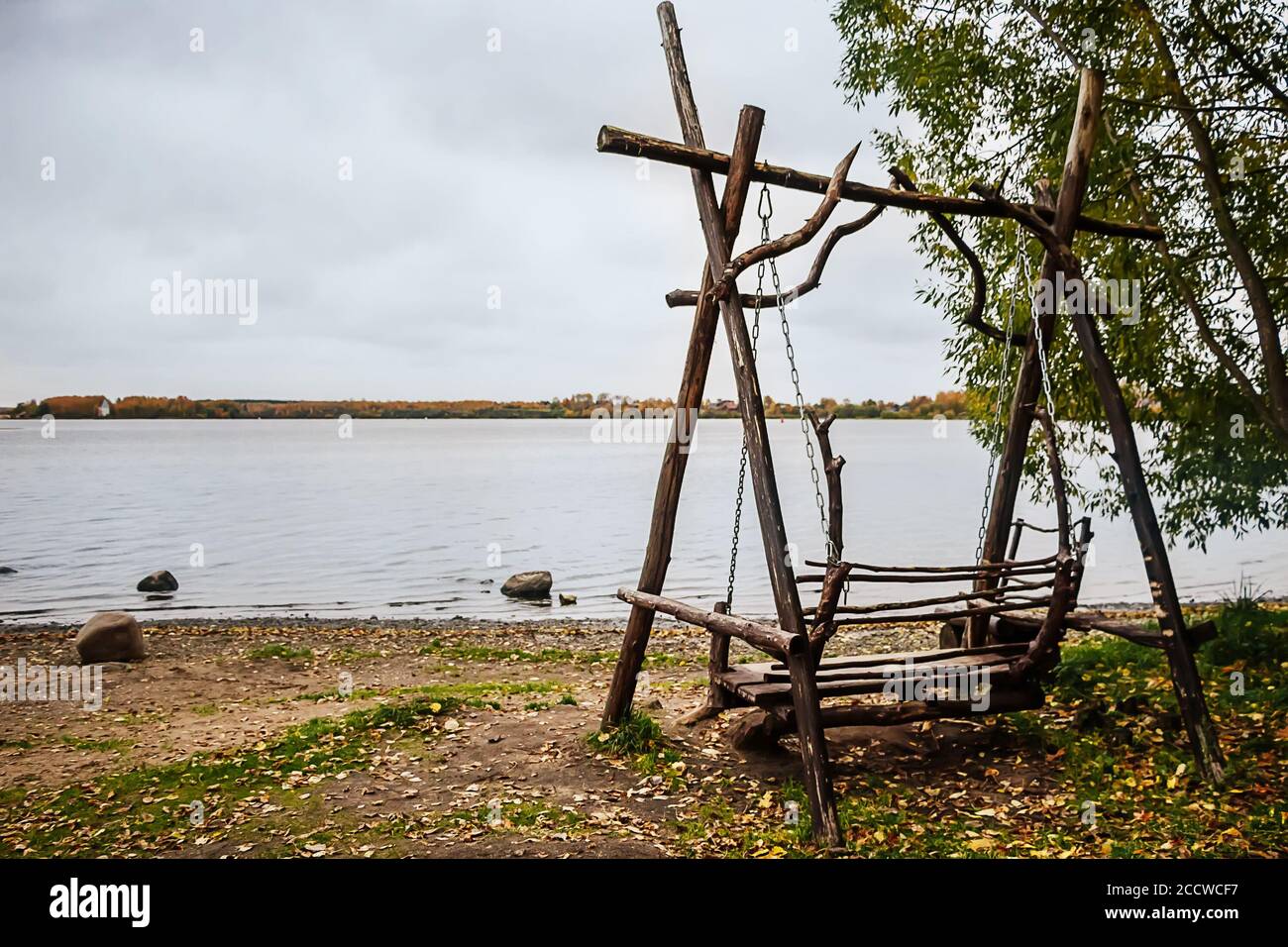 Wooden swing on the lake by autumn cloudy day Stock Photo