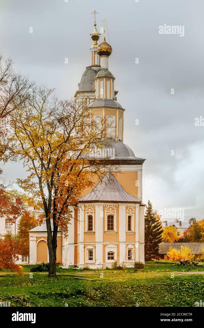 Ancient christian church and autumn yellow trees. Beautiful domes, high bell tower against the sky Stock Photo