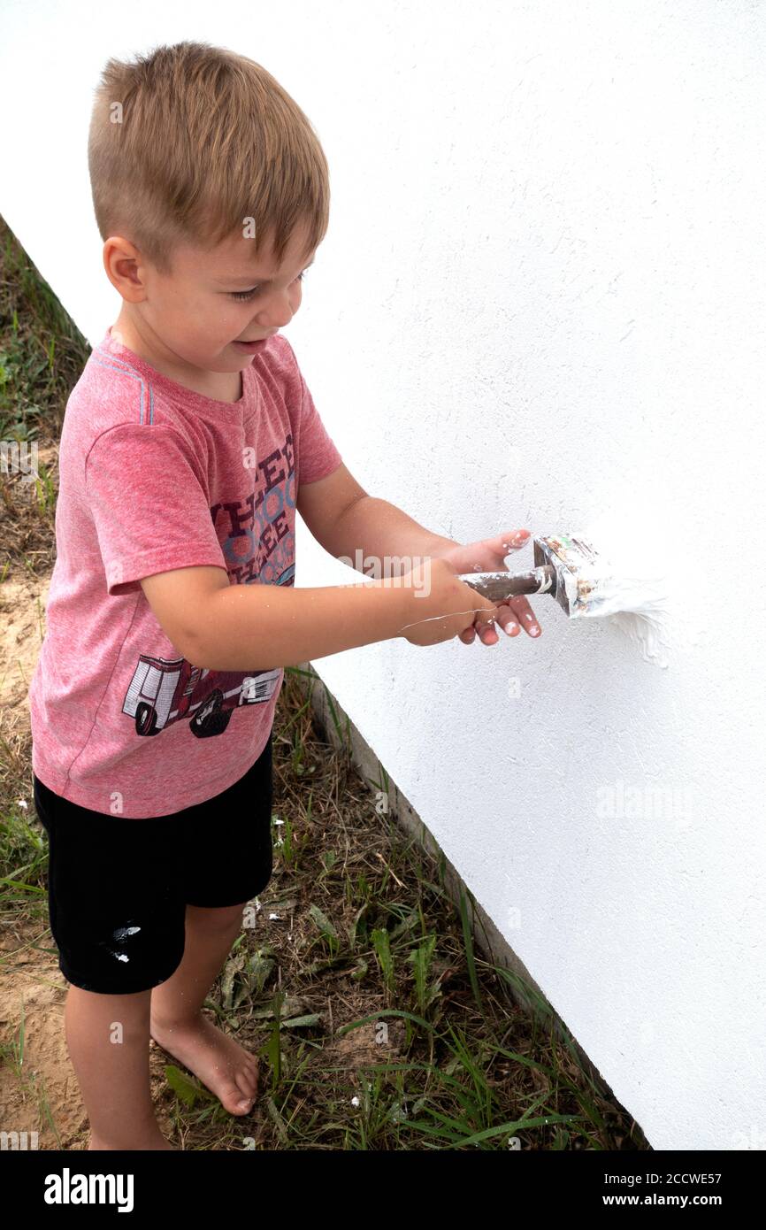 Polish toddler painting the house with a hand roller. Zawady Gmina Rzeczyca Poland Stock Photo