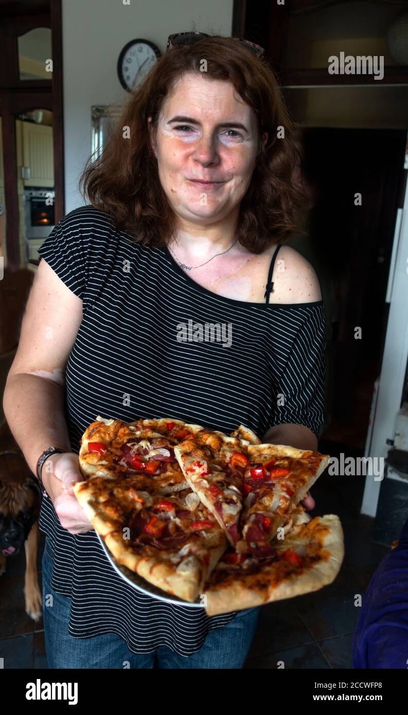 Attractive Polish woman bringing pizza that she just cooked to the table at home. Zawady Gmina Rzeczyca Poland Stock Photo