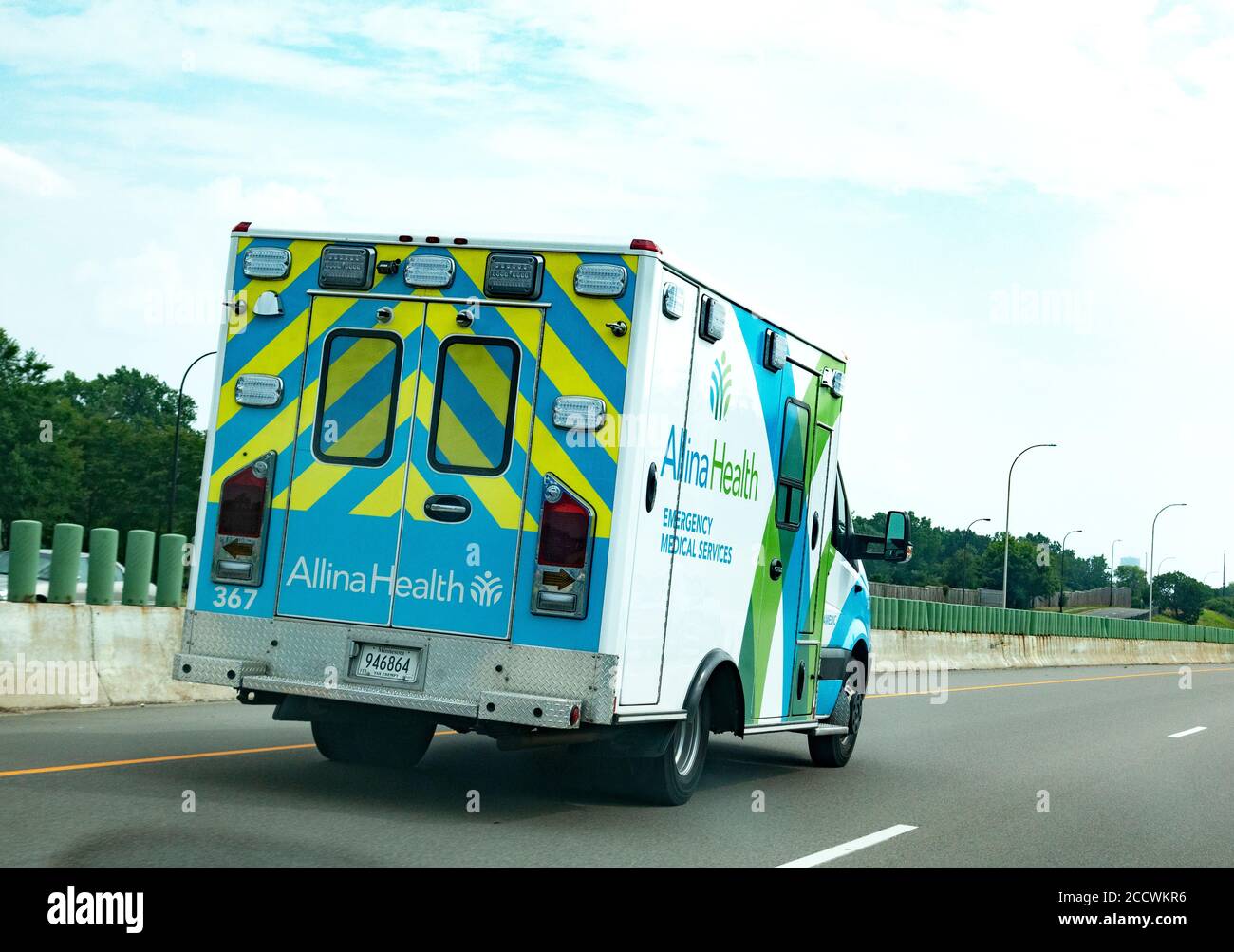 Yellow and blue striped Alina Health emergency medical services ambulance driving on the highway. Minneapolis Minnesota MN USA Stock Photo