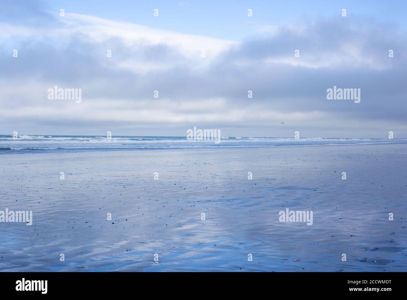 A wintery calm day at Waikuku Beach, Canterbury, New Zealand, with gentle waves, sand and a cloudy sky Stock Photo