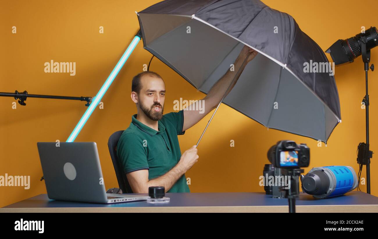 Professional photographer recording umbrella review in studio. Professional studio video and photo equipment technology for work, photo studio social media star and influencer Stock Photo