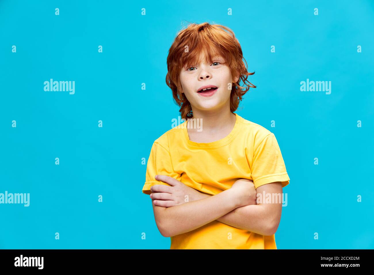 A boy with red hair holds his crossed arms across his chest Stock Photo
