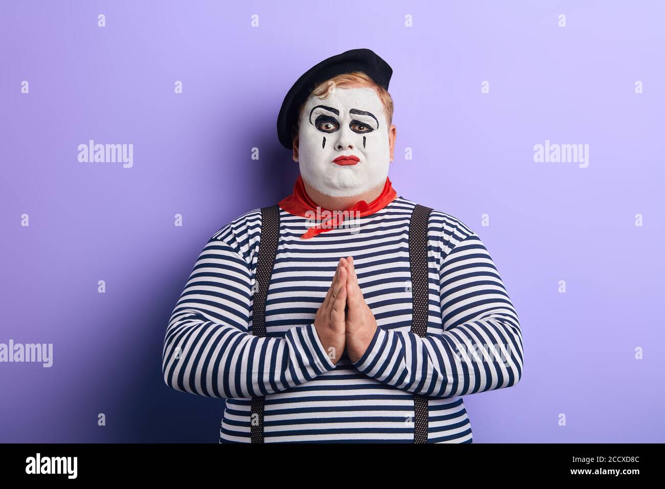 clown in stiped clothes and suspender asking to forgive him. facial expression. close up photo Stock Photo