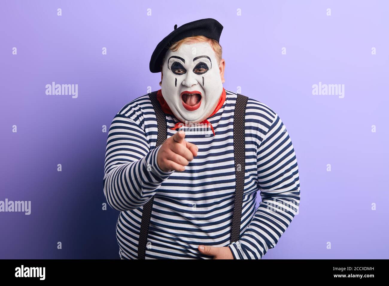 laughing crazy plump mime with wide open mouth points with finger at you, happiness, emotion and feeling. close up portrait, isolated blue background, Stock Photo