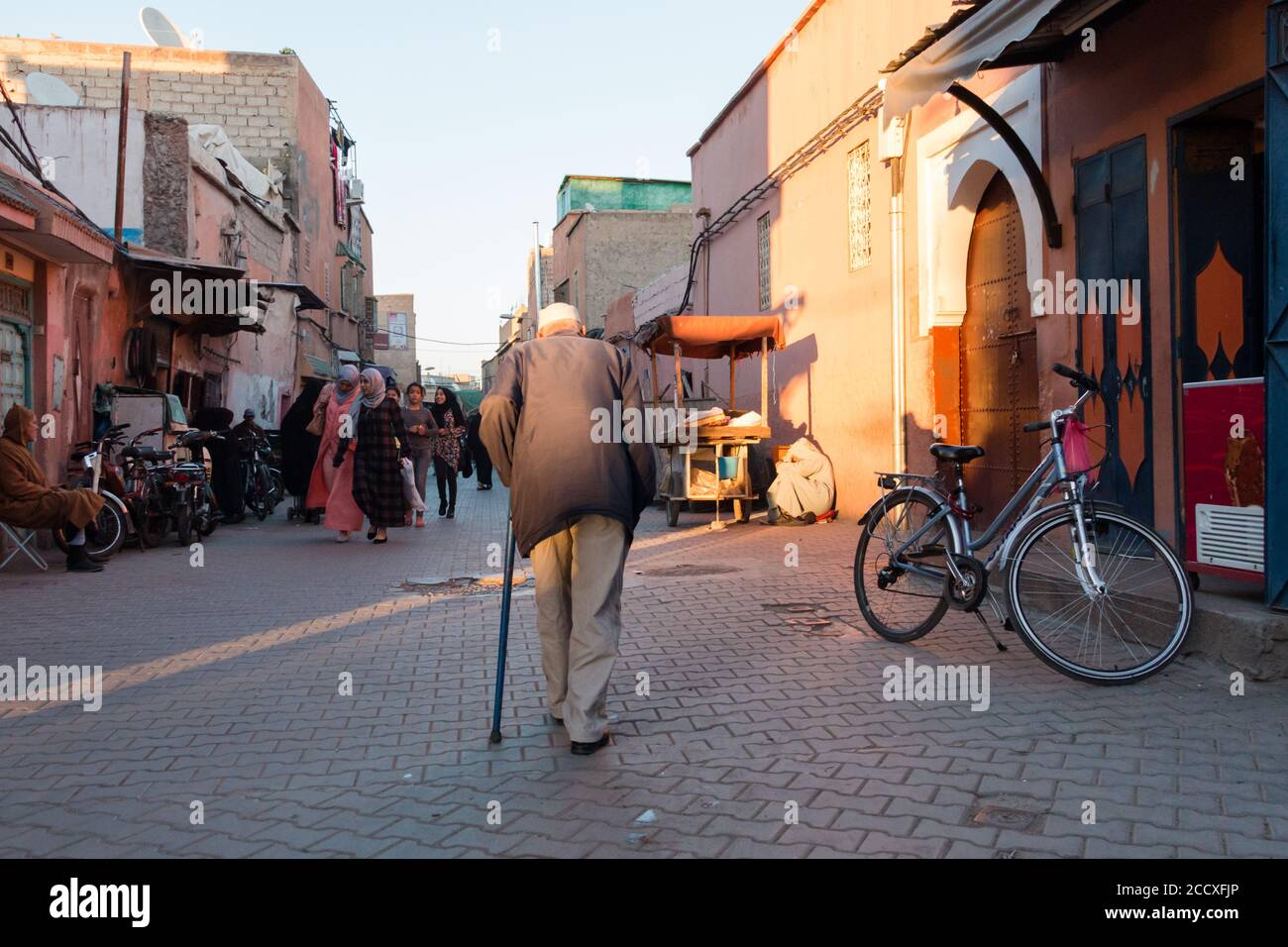 Marrakesh, Morocco - March 13, 2018: An older man walk hunched down the streets of the medina of Marrakech Stock Photo