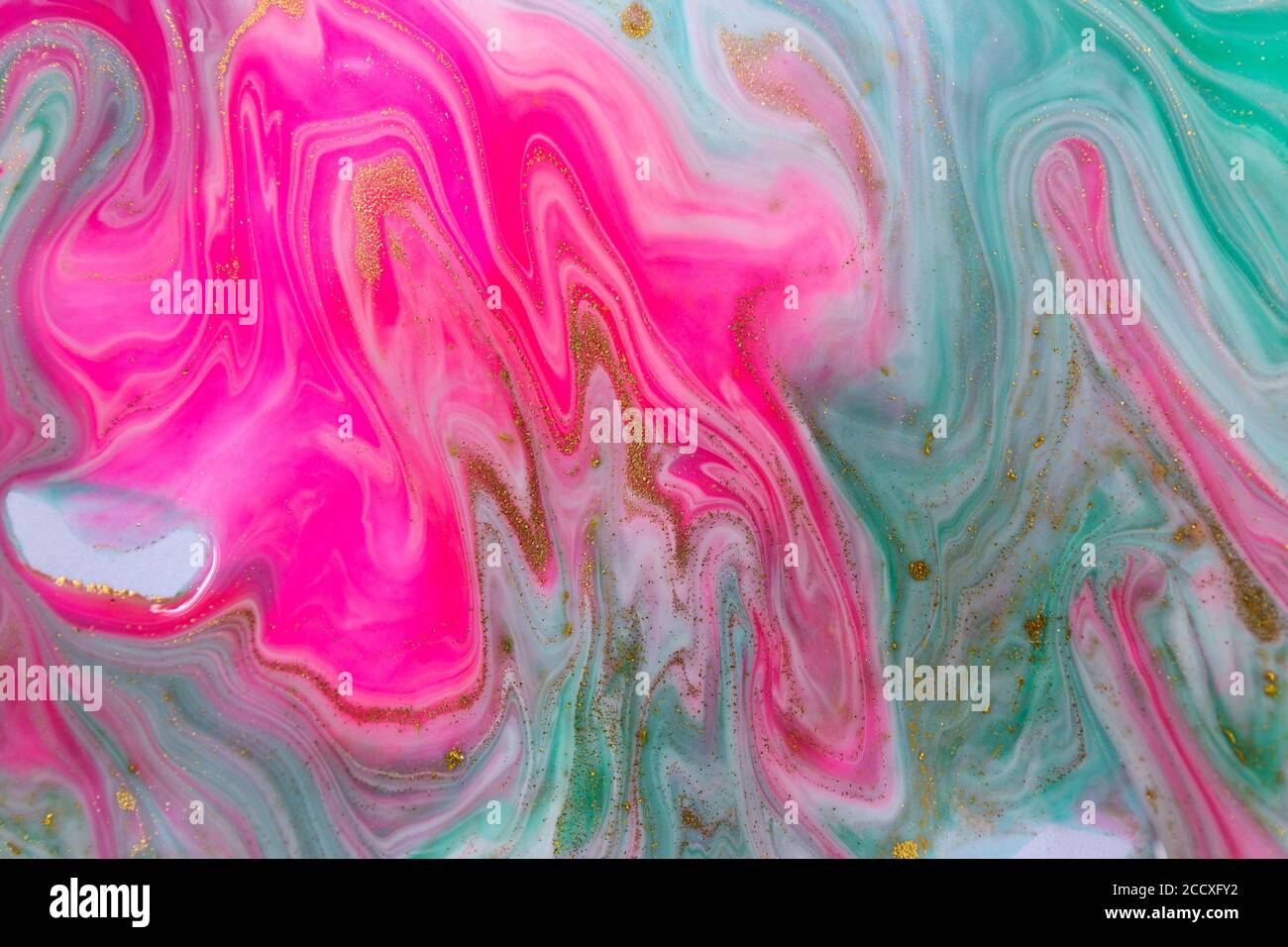 Pink, gold and green mixed inks spilled on white paper background