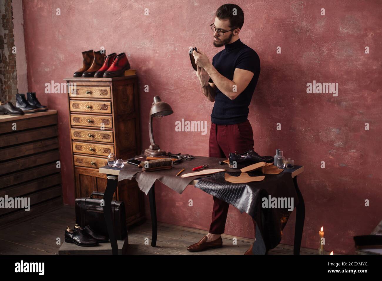 gorgeous pleasant bootmaker holding a shoe at shoemaker's shop. full length photo Stock Photo
