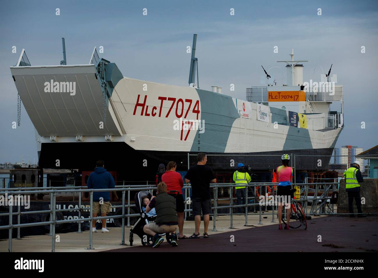Portsmouth, Hampshire, UK. 24th Aug 2020. Bystanders watch the LCT 7074, the last surviving amphibious landing craft tank, before it is moved to the D-Day Museum in Portsmouth, Monday August 24, 2020.  The craft which originally carried tanks and soldiers to Normandy, was floated by barge from the National Museum of the Royal Navy, where it was being restored, to the Promenade in Southsea, where a crane built a bridge to the barge, so it could be driven to its new home at the D-Day Museum. Credit: Luke MacGregor/Alamy Live News Stock Photo