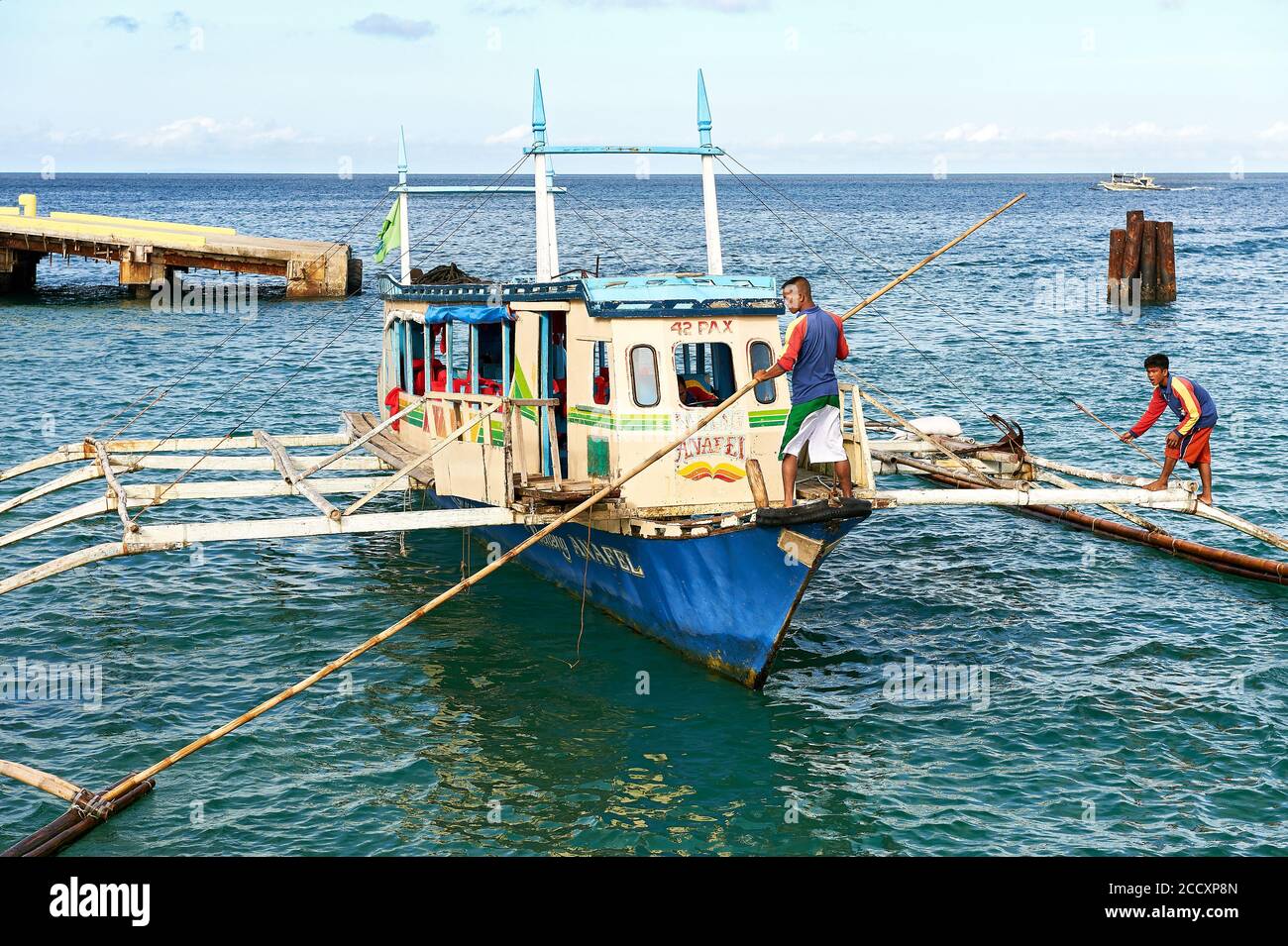 Caticlan pier, Aklan, Philippines: Typical outrigger boat with boatmen arriving at the port of Caticlan, the gateway to Boracay Stock Photo
