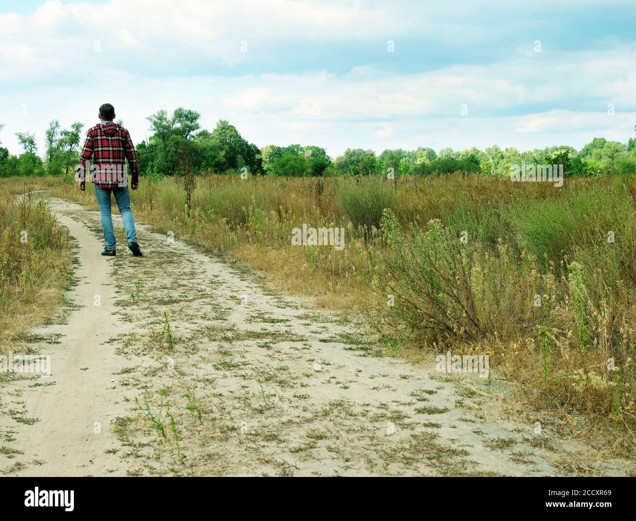 Tourist walks along a path in an autumn field. Tourism and searches. Stock Photo