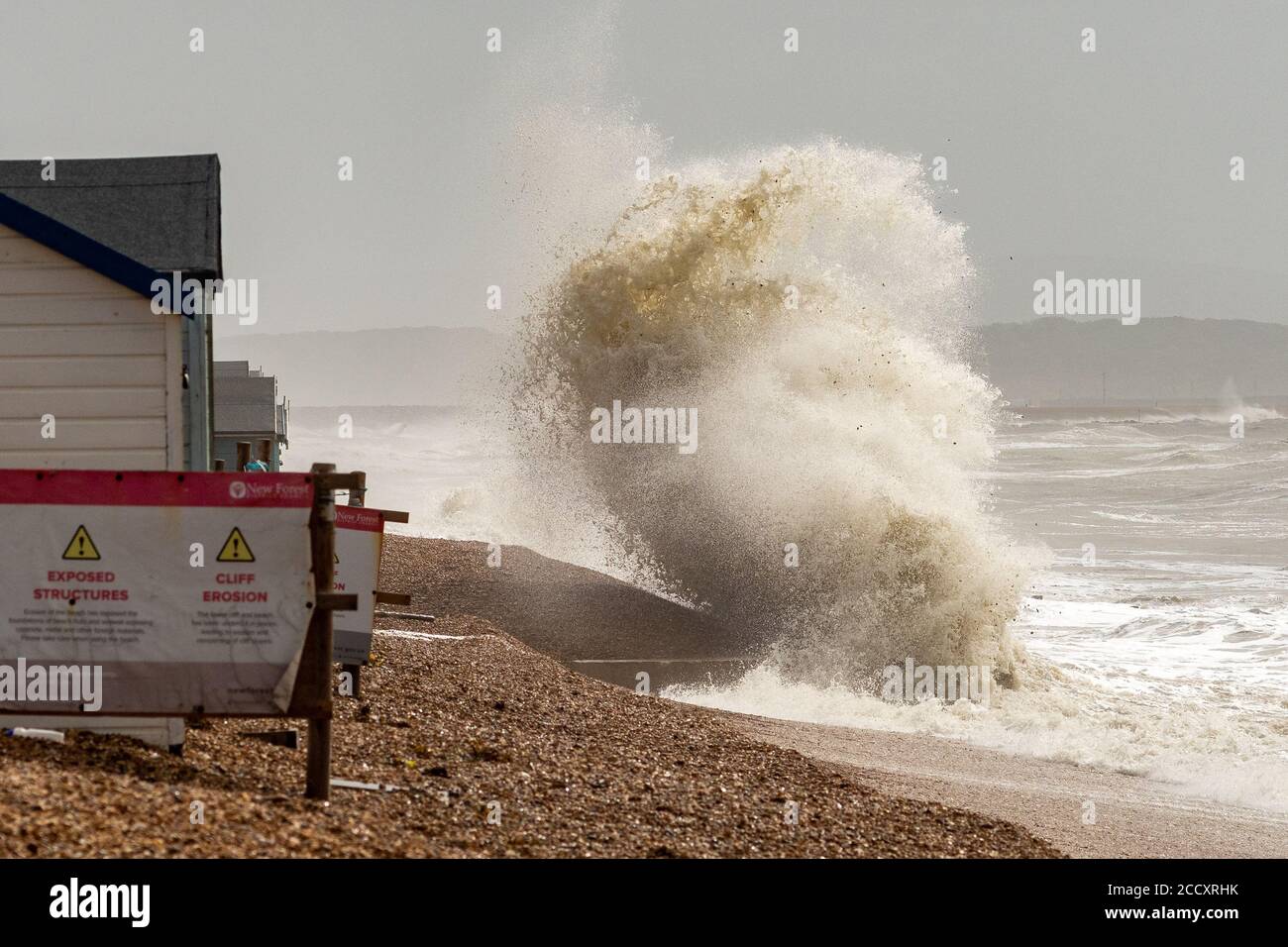 Crashing wave close to beach huts at Milford-on-Sea, Hampshire during Storm Ellen Stock Photo