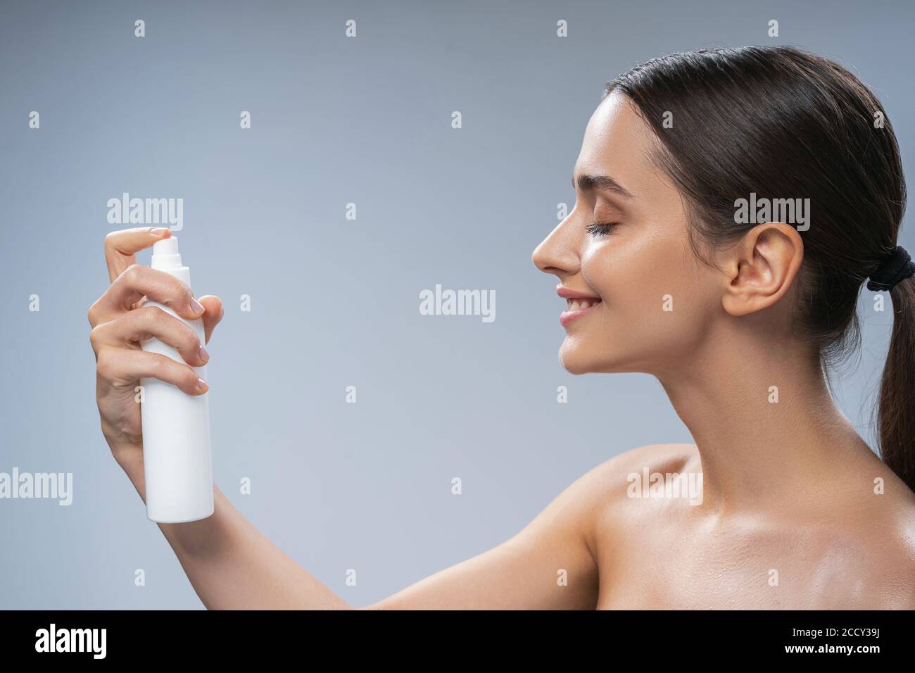 Woman spraying thermal water on her skin Stock Photo