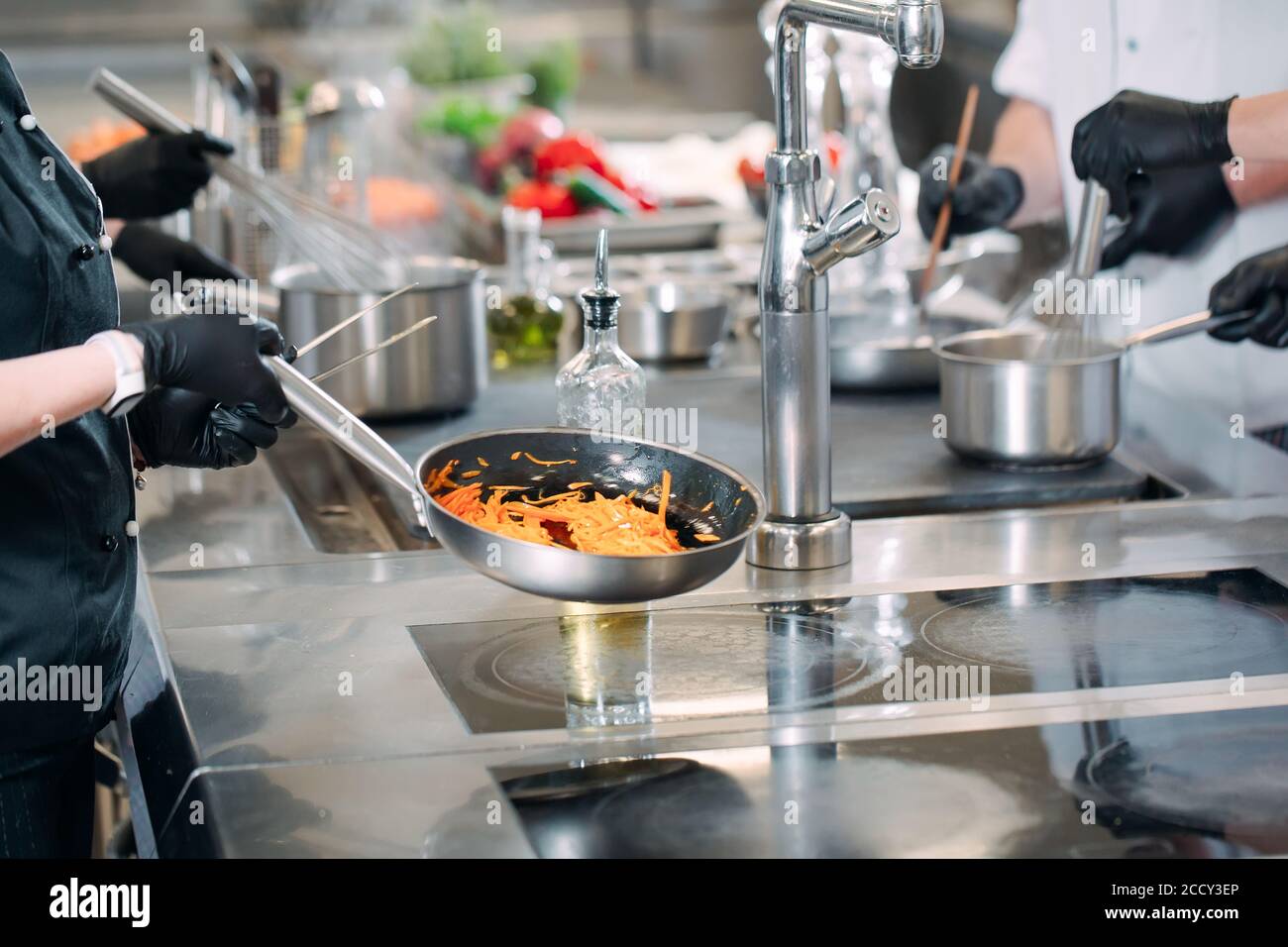 Cooks prepare meals on an electric stove in a professional kitchen in a