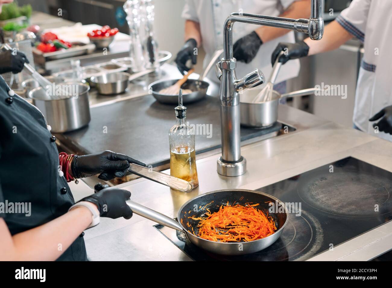 Cooks prepare meals on an electric stove in a professional kitchen in a