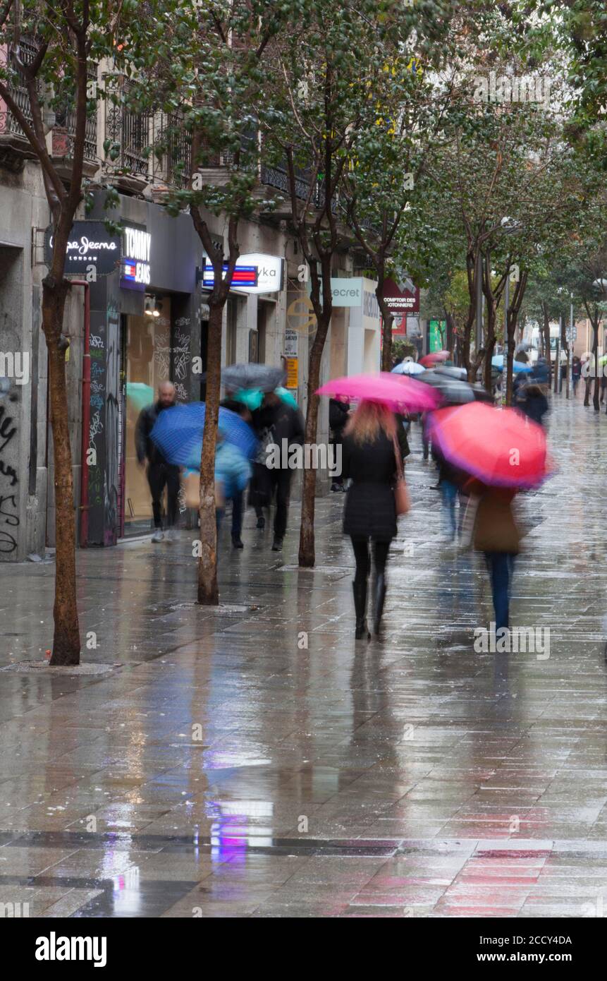 Residents and tourists walk by the most famous Fuencarral street, a comercial street only for pedestrians, full of shops and food stores, on a rainy Stock Photo