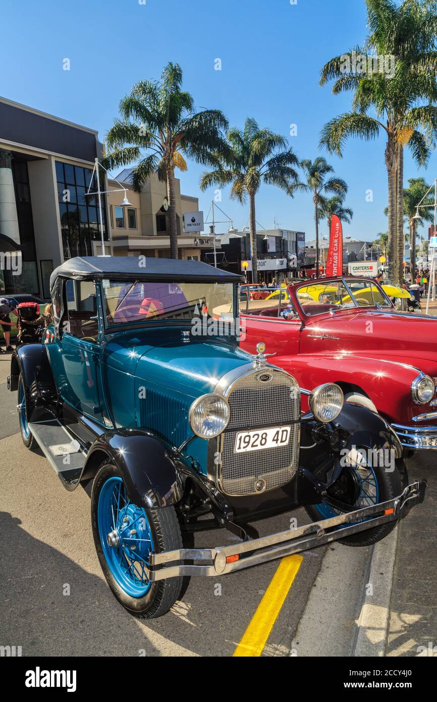 A shiny blue 1928 Ford Model A Roadster, a classic car, on a city
