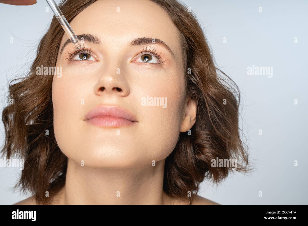 Female with a head tilted back performing a medicine procedure Stock