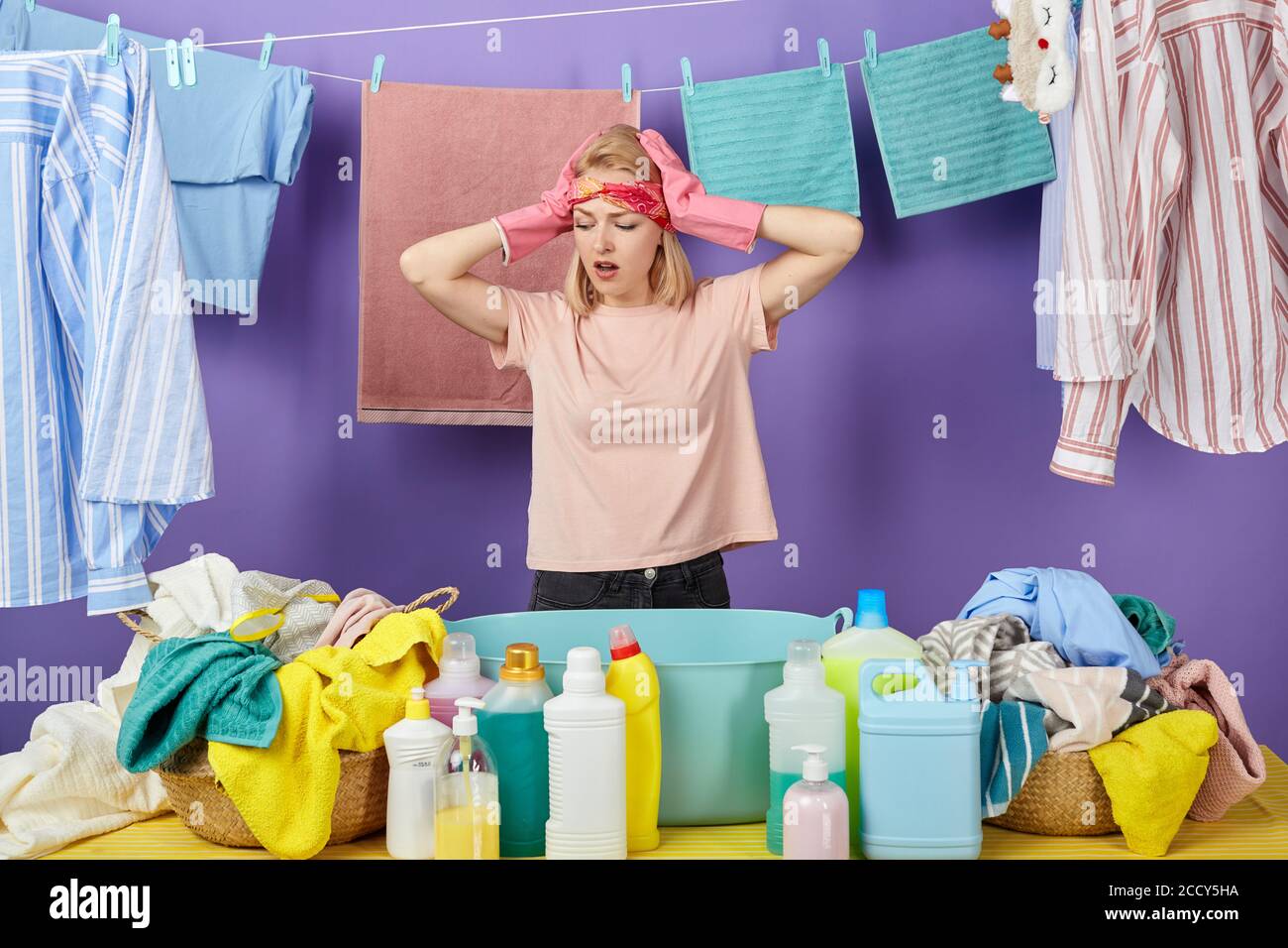 emotional housekeeper being shocked buy many dirty clothes. isolated blue background. desperate woman surprised at quality of detergents. isolated blu Stock Photo