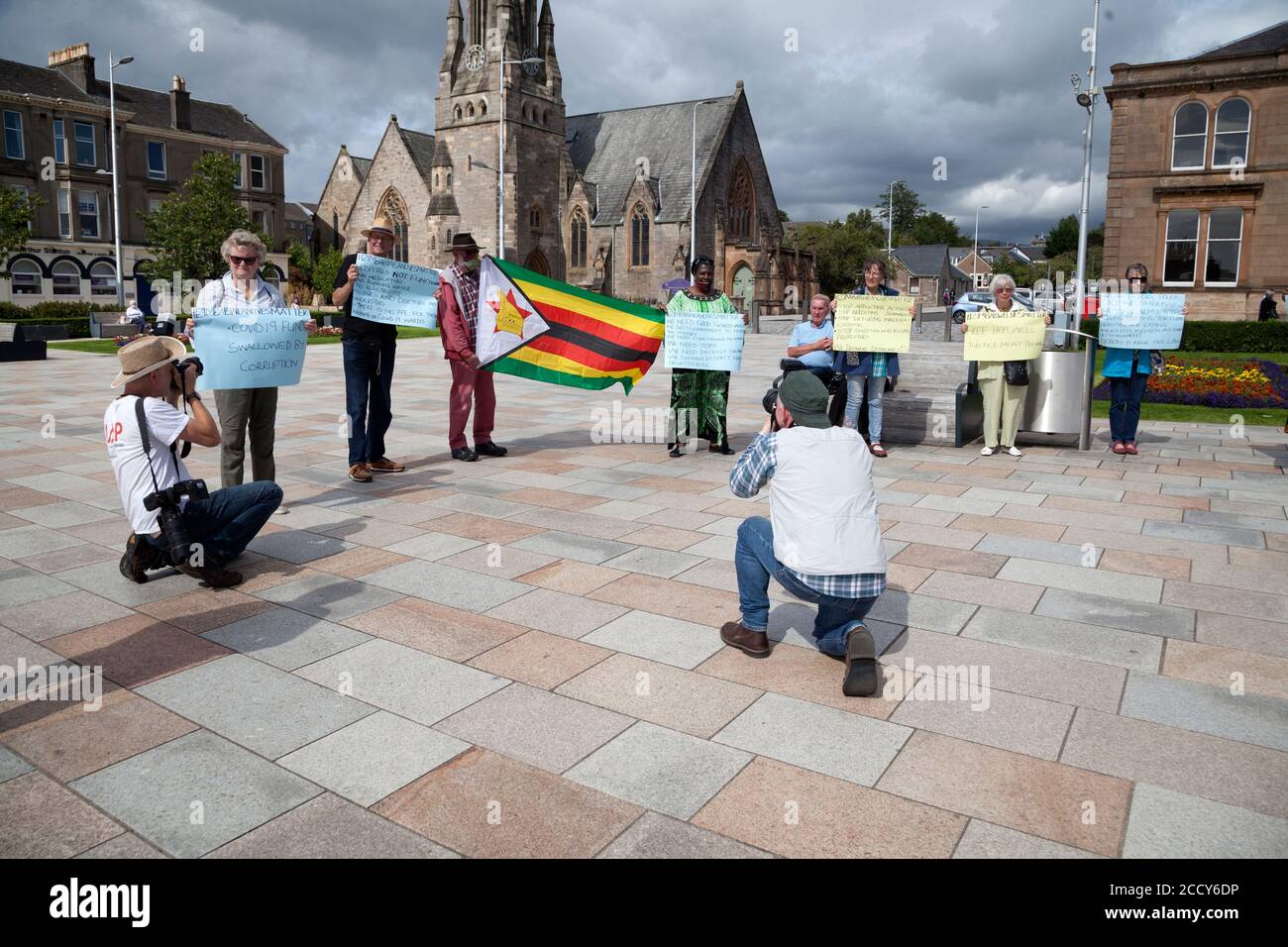 Supporters at the Zimbabwe lives matter protest at Helensburgh, Scotland with placards and flag, with press photographers. Stock Photo