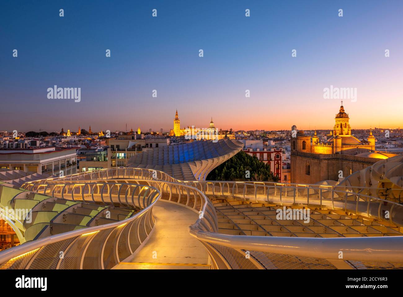 View over Sevilla from Metropol Parasol at sunset, curved wooden construction, Cathedral of Sevilla with tower La Giralda, Iglesia del Salvador and Stock Photo